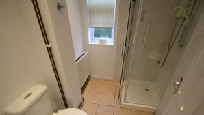 A small bathroom with a toilet, a window, a radiator, and a glass shower enclosure. - Spacious Apartment in Coventry near Belgrade Theatre (Coventry)