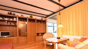 A cozy room with wooden floors, a sofa, a table, and a TV. - Holiday Home With Terrace in Graal-muritz (Graal Mueritz)