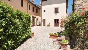 A narrow cobblestone street flanked by traditional buildings with shutters and a stone wall on one side. - Villa in Tuscany With Pool and Wine Tasting (Pergine Valdarno)