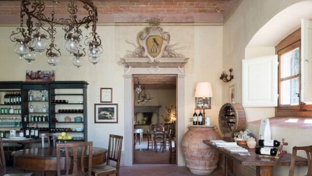 A dining area with a brick floor, wooden furniture, a chandelier, and a wine rack. - Villa in Tuscany With Pool and Wine Tasting (Pergine Valdarno)