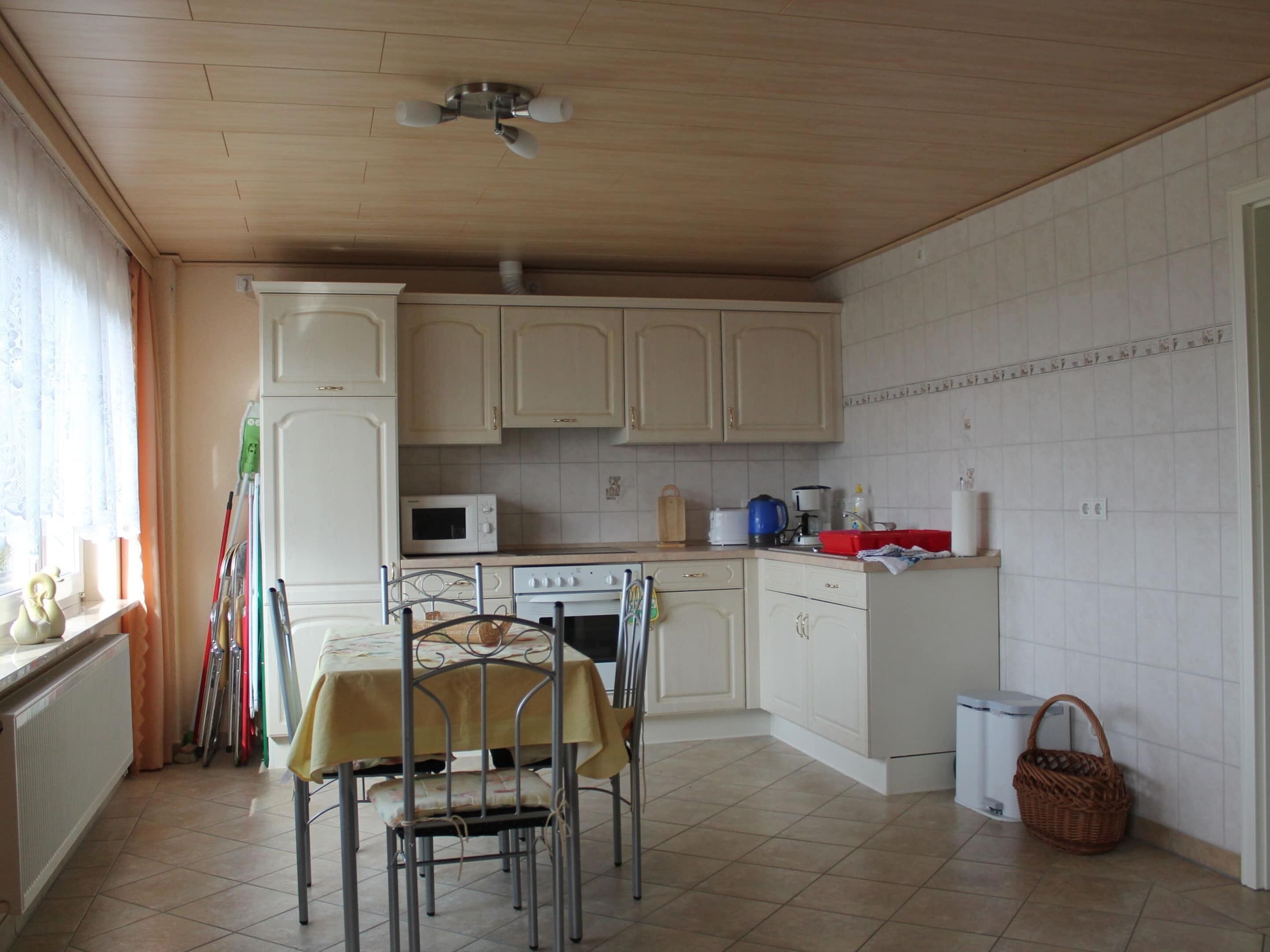 A kitchen with white cabinets, a microwave, a stove, and a dining table with chairs.