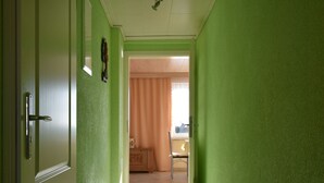 A hallway with green walls and a door leading to a room with a window and curtains. - Rustic Escape in Kropelin (Kroepelin)