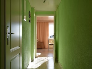 A hallway with green walls and a door leading to a room with a window and curtains. - Rustic Escape in Kropelin (Kroepelin)
