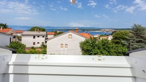 A view from a balcony with a skylight, overlooking a coastal town with houses and a body of water in the distance. - Apartment in Croatian Islands With Stunning Views (Malinska-Dubasnica)