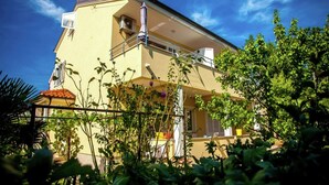 A two-story building with a balcony, surrounded by greenery. - Apartment in Croatian Islands With Stunning Views (Malinska-Dubasnica)