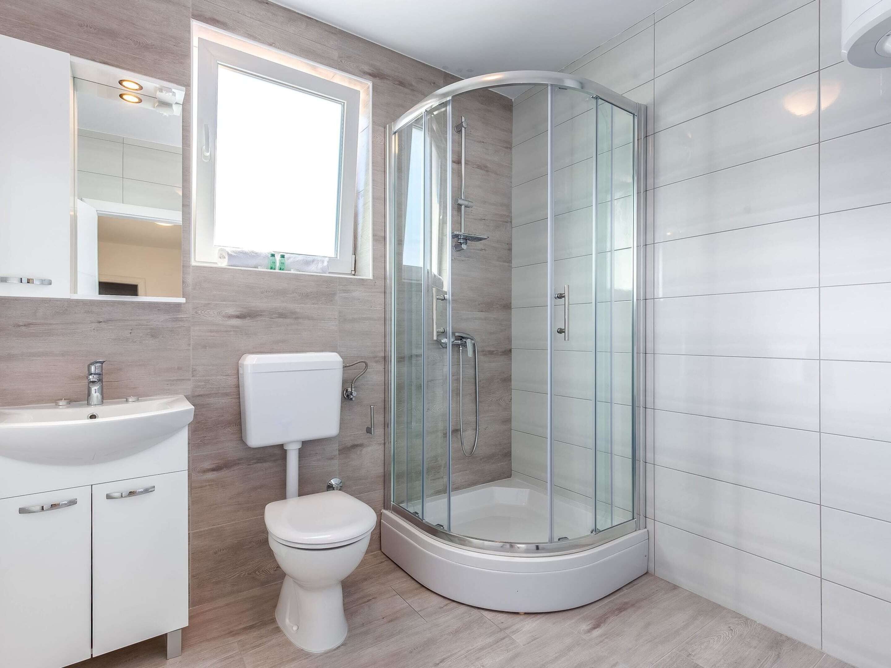 Une salle de bain moderne avec une douche à parois de verre, des toilettes blanches et un lavabo.
