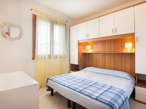 A bedroom with a bed, a bedside table, a mirror, and a wardrobe. - Belvilla by OYO Trilo 1 Solmare a Rosolina (Rosolina)