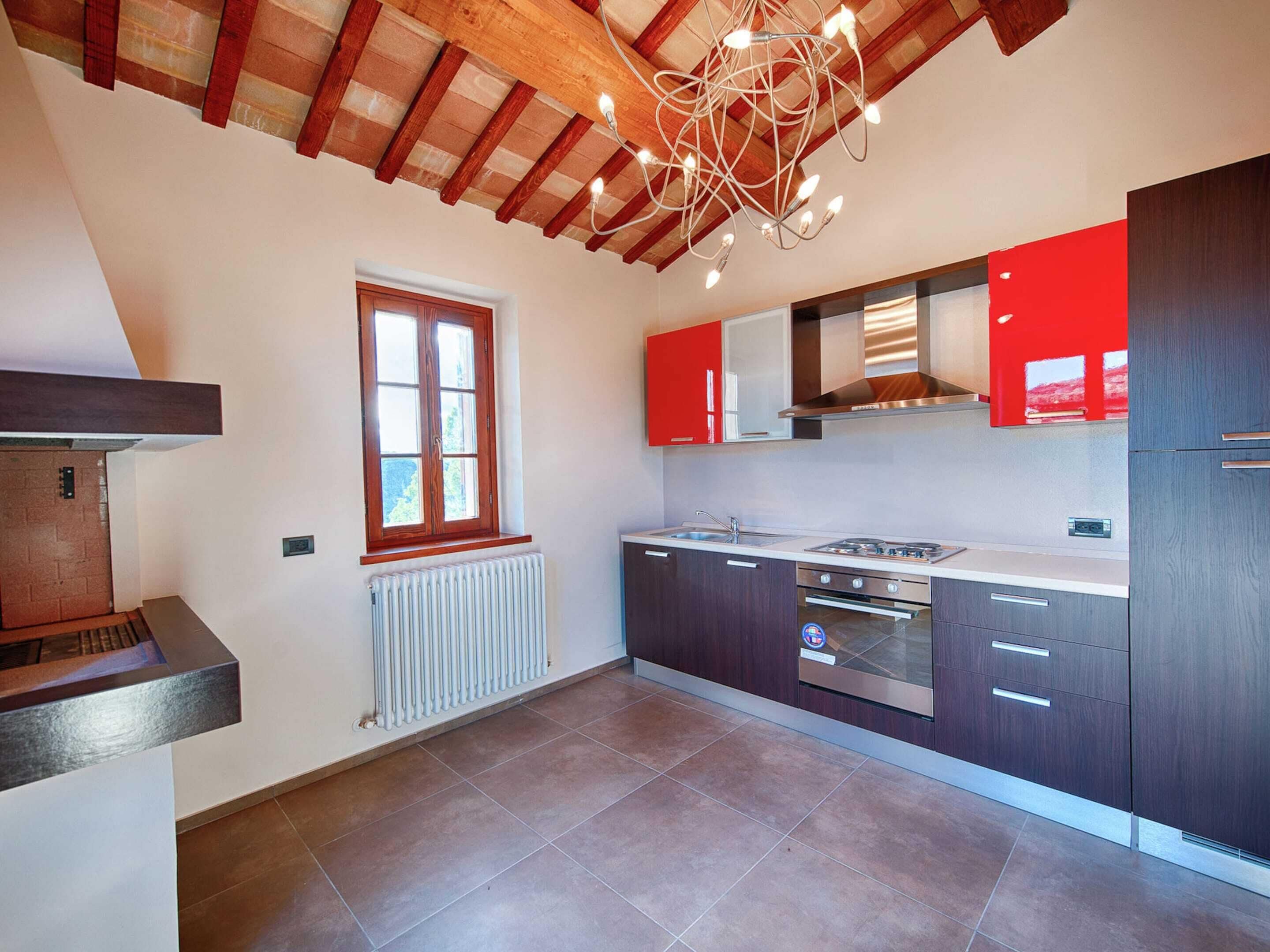 A modern kitchen with dark cabinets, a stainless steel stove, and a window with wooden shutters.