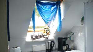 A small kitchen with a window, a toaster, a coffee maker, and a kettle. - Gemutliche Ferienwohnung mit Garten in Walkendorf (Walkendorf)