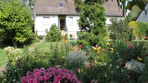 A house surrounded by a well-maintained garden with various flowers and shrubs. - Gemutliche Ferienwohnung mit Garten in Walkendorf (Walkendorf)