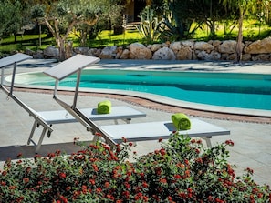 Ein Poolbereich mit Liegestühlen und einer Steinmauer.