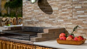 A stone wall with a built-in grill and a basket of fruit on a ledge. - Rustic Villa With Pool, Sicily (Castellammare del Golfo)