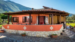 A rustic house with a stone foundation, wooden beams, and a tiled roof. It features a covered porch with outdoor seating and potted plants. - Rustic Villa With Pool, Sicily (Castellammare del Golfo)