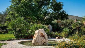 A garden with a central rock feature, a small pond, and surrounding greenery. - Rustic Villa With Pool, Sicily (Castellammare del Golfo)