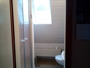 A bathroom with a toilet, a radiator, and a window. - Eine Gemutliche Ferienwohnung in Wismar (Wismar)