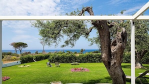 An outdoor dining area with a view of the sea, a large tree, and a well-maintained lawn. - Elegant House in Cefalù, Near the Sea With Stunning Views and Garden! (Cefalù)