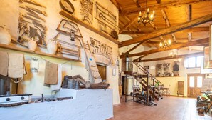 A rustic interior with wooden beams, a staircase, and various antique tools and equipment displayed on the walls. - Holiday Home in Guardavalle by River (Stilo)