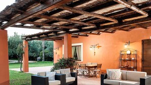 An outdoor patio with wicker furniture, a table, and a bookshelf. - Belvilla by OYO Villa Arangea Dieci (Marsala)