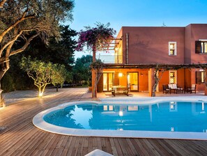 Ein Poolbereich mit Holzterrasse, Pool und einem Gebäude mit Balkon.