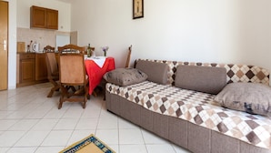 A living room with a sofa, a dining table with chairs, a kitchen area, and a tiled floor. - Nice Apartment With Terrace Near the Beach (Malinska-Dubasnica)