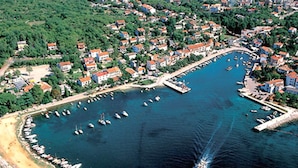 An aerial view of a coastal town with a marina, numerous boats, and residential buildings with red roofs. - Nice Apartment With Terrace Near the Beach (Malinska-Dubasnica)
