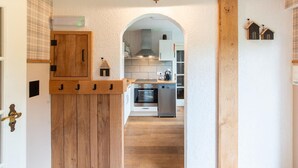 A hallway with wooden cabinets, a kitchen area with modern appliances, and a small decorative house on the wall. - Charming House With Sauna, Jacuzzi in Bullange (Buellingen)