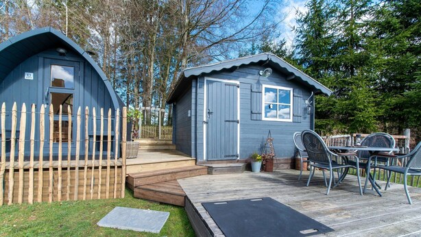 A small, two-story cabin with a deck and outdoor seating area. - Charming House With Sauna, Jacuzzi in Bullange (Buellingen)