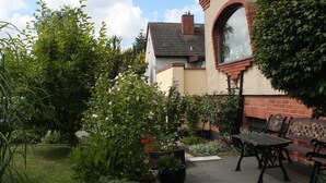 A garden with a patio area, including a table and chairs, and a brick wall with a window. - Wohnung mit Eigener Terrasse in Wismar (Wismar)