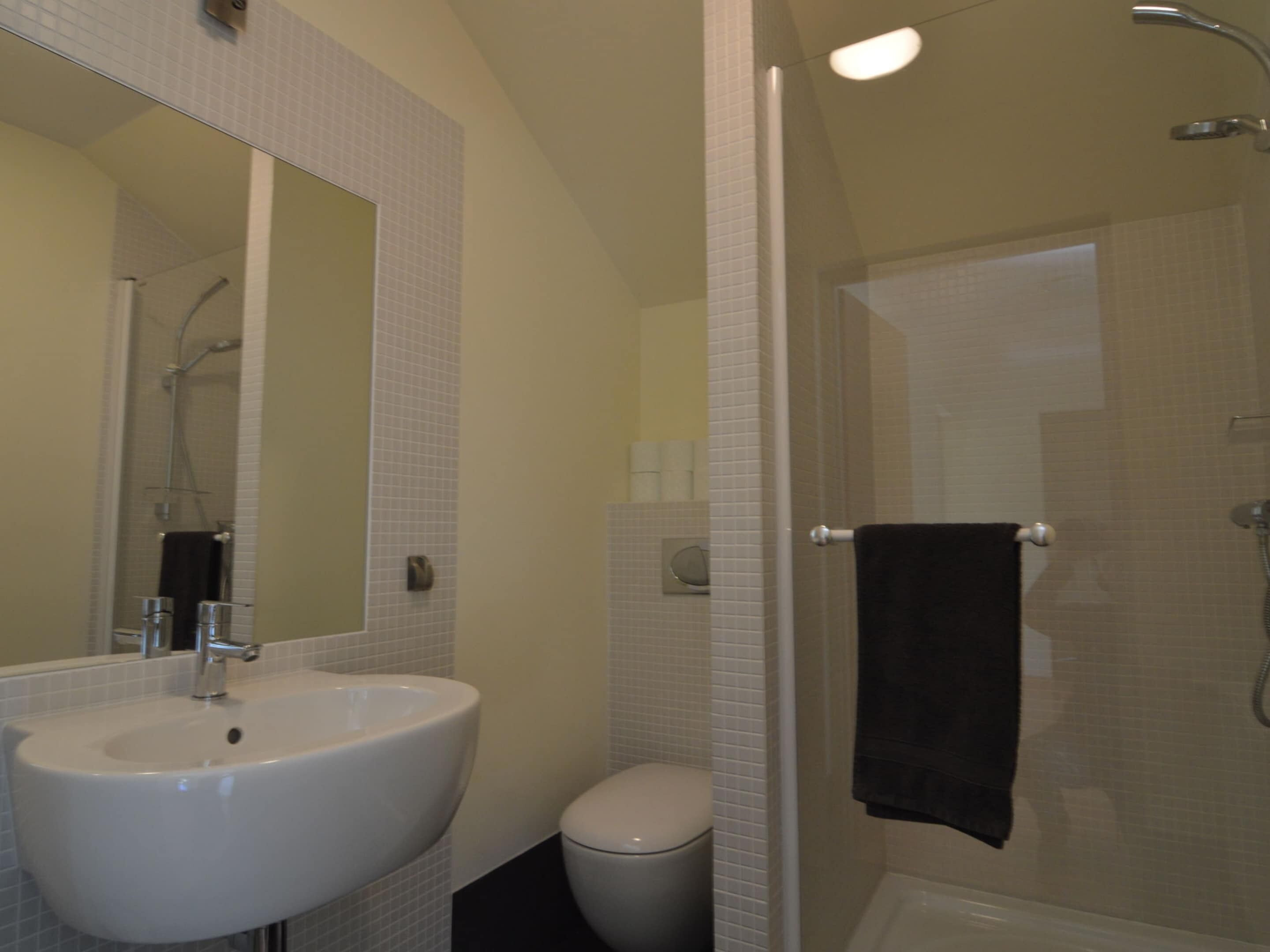 Un baño con lavamanos, inodoro y ducha blancos.