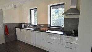 A modern kitchen with white cabinets, a black countertop, and two windows providing natural light. - Modern Villa With Sauna, Right Next to the Lake (Borne Sulinowo)