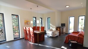 A spacious living area with a dining table, chairs, a sofa, and a television. - Modern Villa With Sauna, Right Next to the Lake (Borne Sulinowo)
