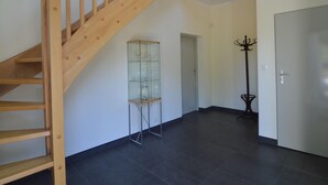 A spacious room with a wooden staircase, a glass cabinet, and a coat rack. - Modern Villa With Sauna, Right Next to the Lake (Borne Sulinowo)