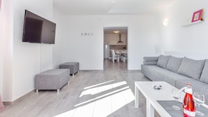 A modern living room with a grey sofa, a white coffee table, and a flat-screen TV mounted on the wall. - Peaceful Villa in Dramalj with Hot Tub (Crikvenica)