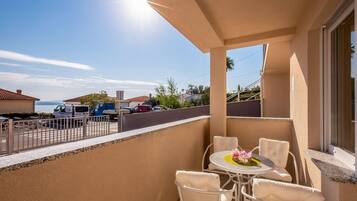 Enjoy the stunning sea view from this balcony, featuring a table and chairs, and a beautiful flower arrangement.