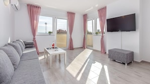 A modern living room with a sofa, a table, a flat-screen TV, and a bench. - Peaceful Villa in Dramalj with Hot Tub (Crikvenica)