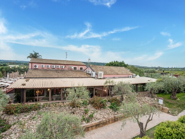 A traditional building with a tiled roof, a stone pathway, and a garden with various plants.