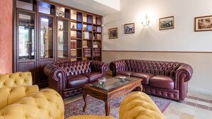 A spacious living room with a large wooden bookcase, two leather sofas, and a glass coffee table. - Holiday Home Sicily With Pool & Sauna (Carlentini)