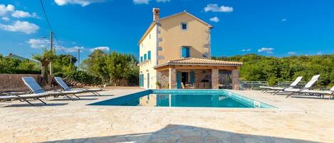 A two-story house with a swimming pool and sun loungers.