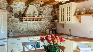 Une cuisine rustique avec des murs en pierre, des poutres en bois et un réfrigérateur blanc.