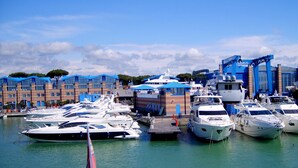 A marina with multiple yachts docked, a building with blue roofs, and a clear sky. - Lucca Retreat With Pool (Lucca)