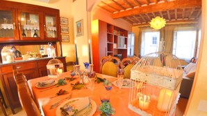 A dining area with a wooden table set for a meal, surrounded by chairs and a decorative birdcage. - Lucca Retreat With Pool (Lucca)