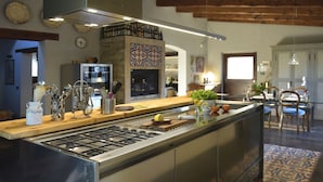 A modern kitchen with a central island, stainless steel appliances, and a variety of utensils and appliances on the countertop. - Belvilla by OYO Villa Colle (Recanati)