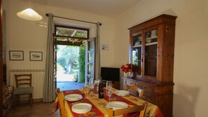 A dining area with a table set for four, a wooden cabinet, and a view of the outdoors. - Belvilla by OYO Mare (Fermo)