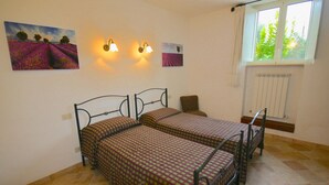 A room with two beds, a chair, and a window with a view of greenery. - Belvilla by OYO Mare (Fermo)