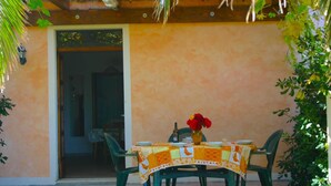 An outdoor patio with a table set for two, covered with a patterned tablecloth, and surrounded by green chairs. - Belvilla by OYO Mare (Fermo)