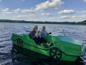 A green boat on a lake with two people and a dog. - Holiday Home by Lake in Nowa Wioska (Lubrza)