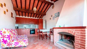Una cucina accogliente con mobili in legno, un tavolo da pranzo con sedie, un divano e un camino in mattoni.