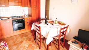 Una cucina compatta con mobili in legno, un fornello a gas e un tavolo da pranzo per due persone.