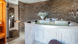 Ein modernes Badezimmer mit freistehender Badewanne, einer Holzbank, einer Duschkabine und einer Steinwand.