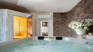 Ein Wellnessbereich mit Whirlpool, Holzwänden und einer Steinwand mit Blumen.